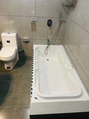 a bathroom with a bath tub and a toilet at The Lotaz Hotel in Cochin