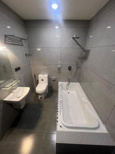 a bathroom with a tub and a toilet and a sink at The Lotaz Hotel in Cochin