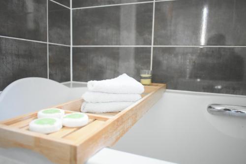 a wooden tray with towels and soap on a bath tub at Luxury 2 Bedroom Northampton Townhouse with Balcony in Northampton