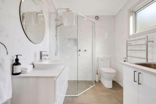 a white bathroom with a sink and a shower at Sahaja Cottage Wentworth Falls in Wentworth Falls