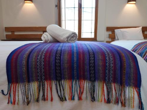 a bed with a colorful blanket on top of it at Maison Fortaleza in Cusco