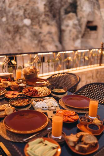 a table with plates of food and candles on it at İsadora Cave Cappadocia in Nevsehir