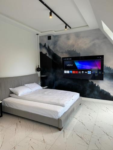 a bedroom with a bed and a tv on the wall at Yeti Studio Apartament Krupówki 73C in Zakopane