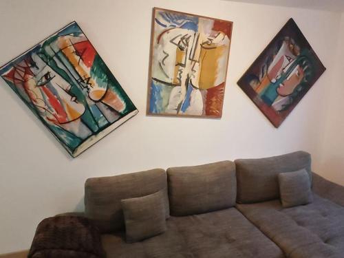 un salon avec un canapé et des tableaux au mur dans l'établissement Appartement Sierentz, à Sierentz