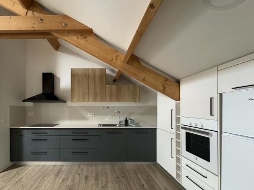 a kitchen with white cabinets and a wooden ceiling at S'apartments in Leiria