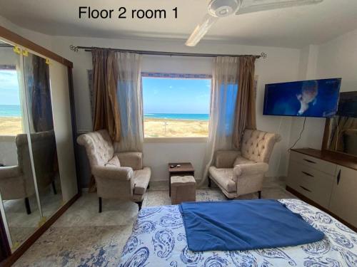 a bedroom with a bed and a view of the ocean at First Row Sea-Front Chalets Media Village in Marsa Matruh