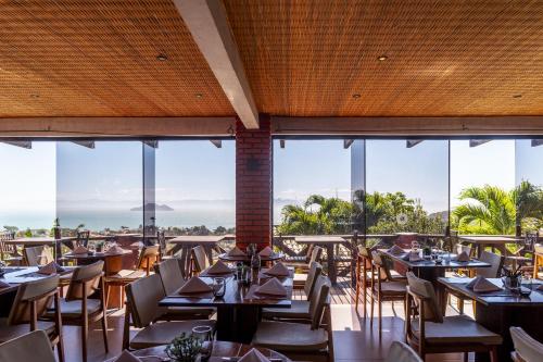 a restaurant with tables and chairs and large windows at Costa do Sol Boutique Hotel in Búzios