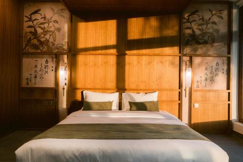 a bedroom with a large bed with wooden walls at THE JAPANESE HOUSE by BRIDGE RETREATS in Ras al Khaimah