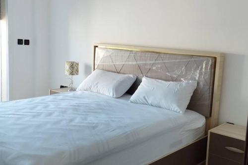 a bed with white sheets and pillows in a bedroom at Appartement Ibn batouta in Gzennaïa