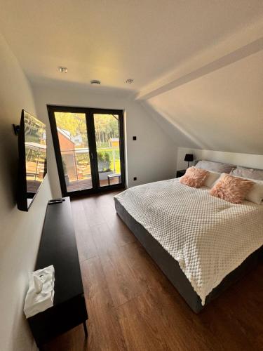a bedroom with a bed and a large window at GrandBytyń House in Nakielno