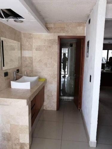 a bathroom with a sink and a person standing in the doorway at Casa Cedros in Mazatlán