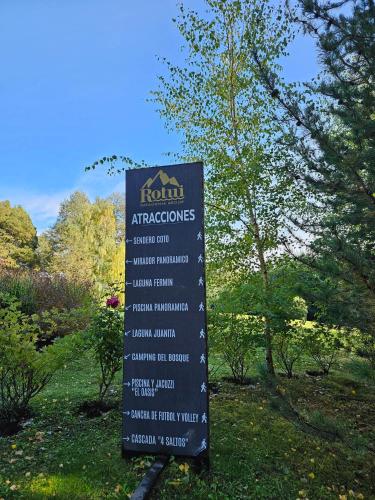 a sign in the grass next to some trees at Rotui Luxury Village in San Martín de los Andes