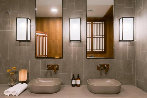 a bathroom with two sinks and two mirrors at THE JAPANESE HOUSE by BRIDGE RETREATS in Ras al Khaimah