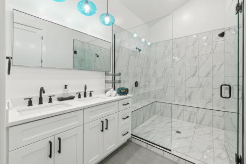a white bathroom with two sinks and a shower at The Hollywood Mansion in Hurricane