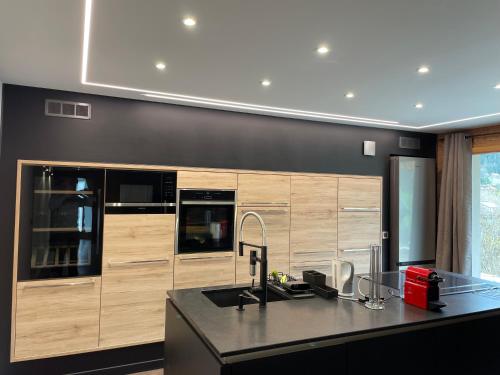 une cuisine avec des armoires en bois et un comptoir noir dans l'établissement Chalet Cristal I, aux Contamines-Montjoie