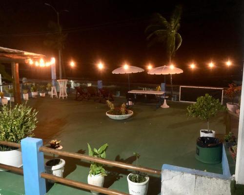 a patio with potted plants and umbrellas at night at Ponta Negra Suites & Apart in Natal