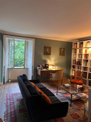 - un salon avec un canapé noir et un bureau dans l'établissement Maison de famille proche St Malo, à Châteauneuf-dʼIlle-et-Vilaine