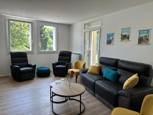 - un salon avec un canapé noir et des chaises dans l'établissement Le repaire du châtaignier, Maison à la campagne, 8 pers, 4 ch, Sidobre, à Ferrières