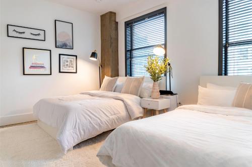 a white bedroom with two beds and a window at Fashion Loft 2 bedroom Downtown in Los Angeles