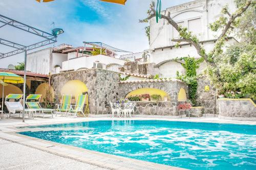 a swimming pool with a table and chairs next to a building at Hotel Annabelle in Ischia