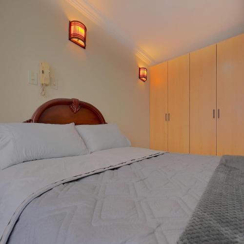 a bedroom with a large white bed with a wooden headboard at Departamento en el Centro con Garaje in Loja