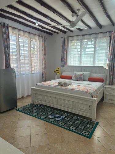 a bedroom with a large bed in a room with windows at Sea la vie - Macheo in Ukunda
