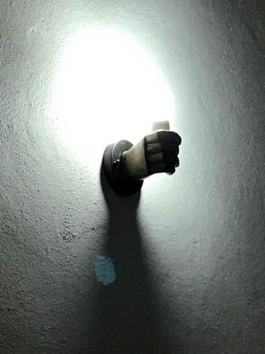 a persons hand holding a light on a wall at Trotamundos in San Juan