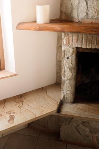 a stone fireplace with a wooden shelf on top at Il Mulino di Nonna Sà - Prestige Private Villa in Pietrasanta