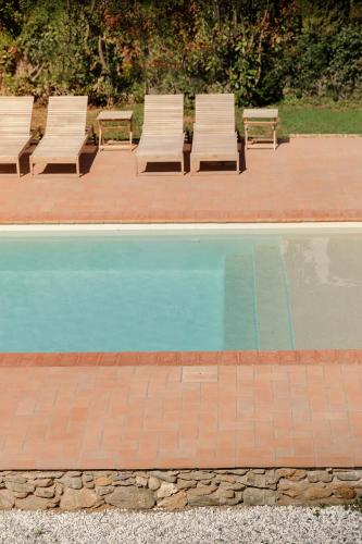 a group of chairs sitting next to a swimming pool at Il Mulino di Nonna Sà - Prestige Private Villa in Pietrasanta