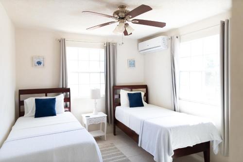 a bedroom with two beds and a ceiling fan at Seashades 2BR 1 full and 1 half bathrooms Condo with pool Close to beach Sleeps 4 in Christ Church