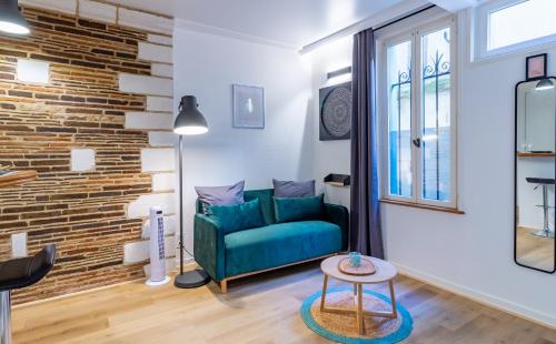 a living room with a green couch and a brick wall at La Maison Verte -Hypercentre-confort in Troyes
