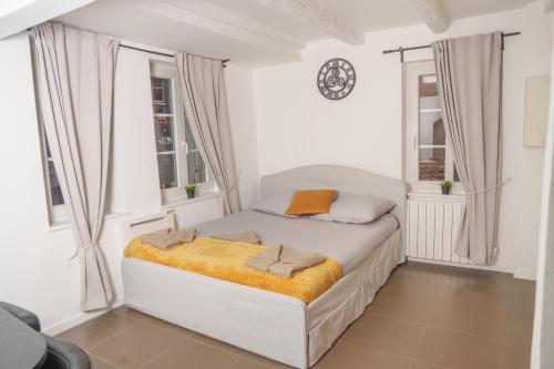 - une chambre blanche avec un lit et une couverture orange dans l'établissement Appartement au Cœur de Strasbourg, à Strasbourg