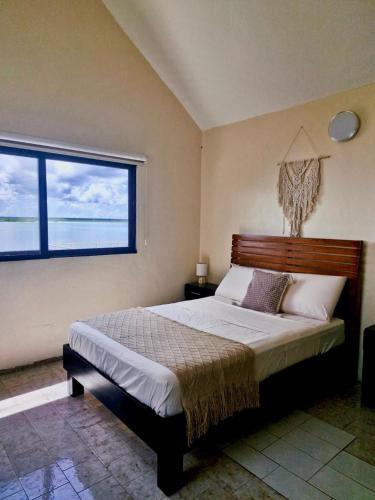 a bedroom with a large bed with a large window at Casa Sirena - Habitaciones a orilla de la Laguna y Cenote Esmeralda in Bacalar