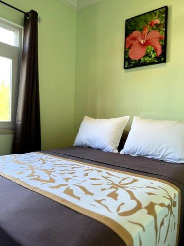 a bedroom with a bed with a flower picture on the wall at Fare Apetahi - Maison 2 Chambres in Uturoa