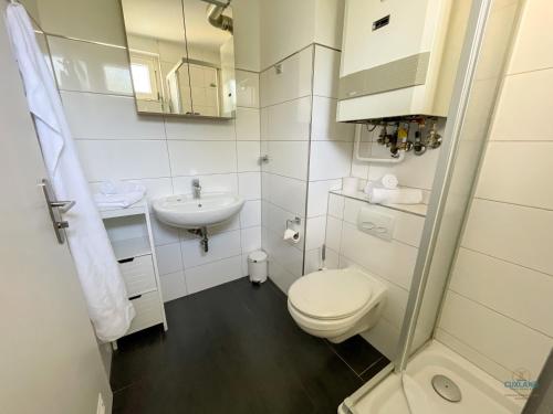 a white bathroom with a toilet and a sink at Haus Nautic Döse Wohnung 301 in Cuxhaven