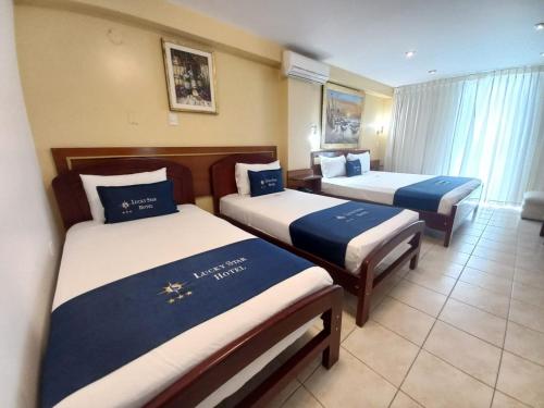 a hotel room with two beds with blue and white sheets at Lucky Star Hotel in Chiclayo