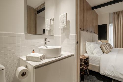 a white bathroom with a sink and a bed at Myla Roma Norte in Mexico City