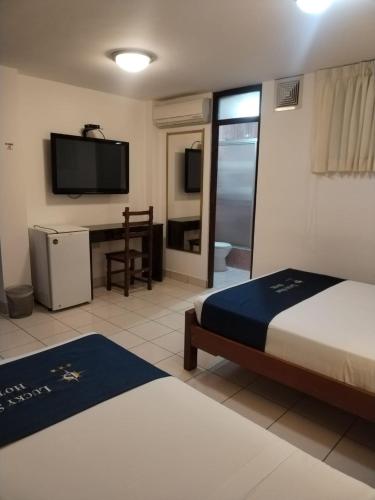 a hotel room with two beds and a flat screen tv at Lucky Star Hotel in Chiclayo