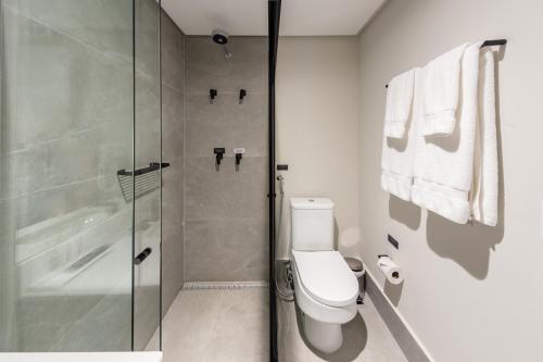 a bathroom with a toilet and a glass shower at Charlie On The Parc Ibirapuera Hotel in Sao Paulo