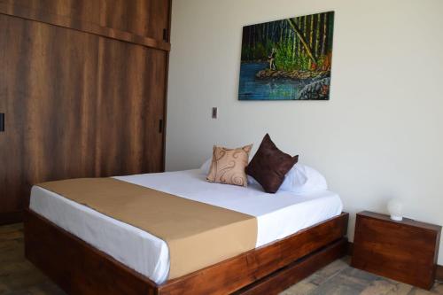 a bedroom with a bed with white sheets and brown pillows at Montecielo Hosting in Guatapé