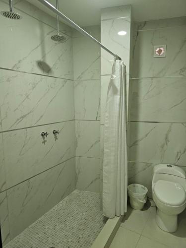 a white bathroom with a toilet and a shower at HOTEL PLAZA in La Paz