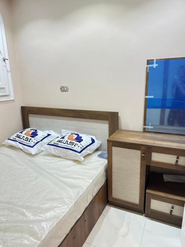 a bedroom with a bed with two pillows and a tv at فيلا بحمام سباحة مارينا 6 الساحل الشمالي العلمين in El Alamein