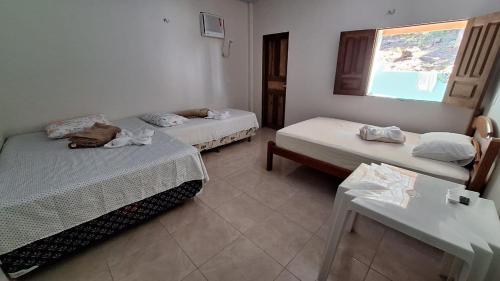 Una habitación con dos camas y una mesa y una ventana. en Casa Toca do Tatu, en Manacapuru