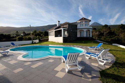a swimming pool with two chairs and a house at Pico Dreams in São Roque do Pico