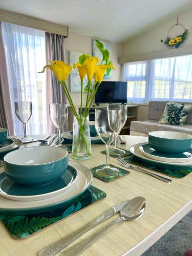 a dining table with yellow flowers in a vase at Lyons Robin Hood , Rhyl in Rhyl