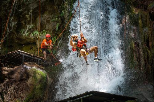 a group of people rappelling from a waterfall at Hacienda Guachipelin Volcano Ranch Hotel & Hot Springs in Liberia