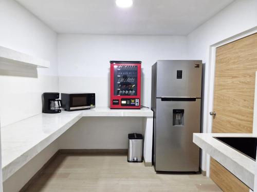 eine Küche mit einem Kühlschrank aus Edelstahl und einer Mikrowelle in der Unterkunft Encantadora Confortable Hab Familiar cerca Forum Majadas y Miraflores H14 in El Rodeo