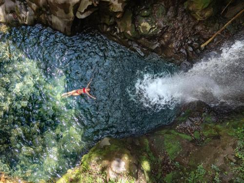 a man swimming in a river in a waterfall at Hacienda Guachipelin Volcano Ranch Hotel & Hot Springs in Liberia