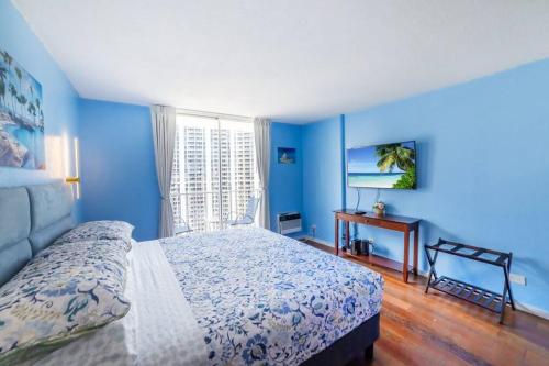 a bedroom with blue walls and a bed and a desk at Trendy Studio in the Heart of Honolulu - 21F in Honolulu