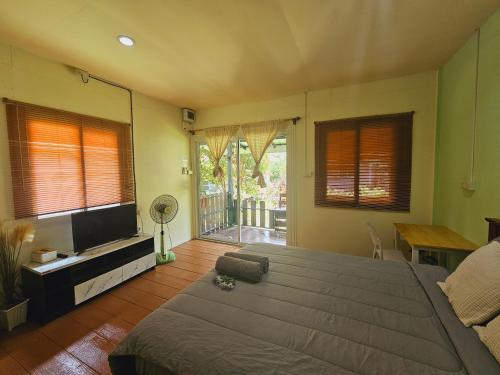 a bedroom with a large bed and a flat screen tv at Baan suan khun ta บ้านพักสวนคุณตา in Ko Chang